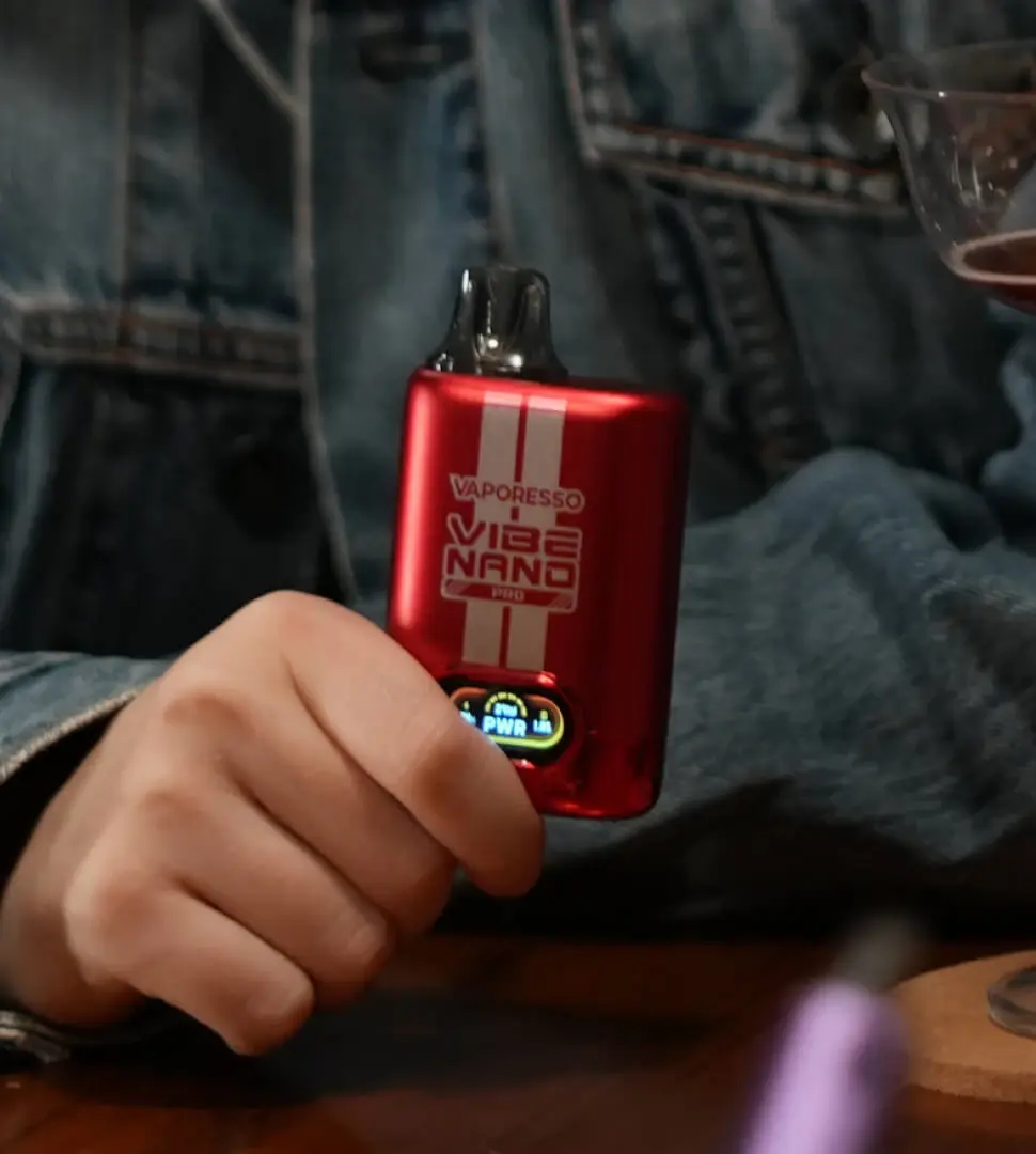 A man vaping indoors in the evening with the VAPORESSO VIBE, showcasing its 4.5ml pod designed to last for vaping needs from morning until night on a single fill.